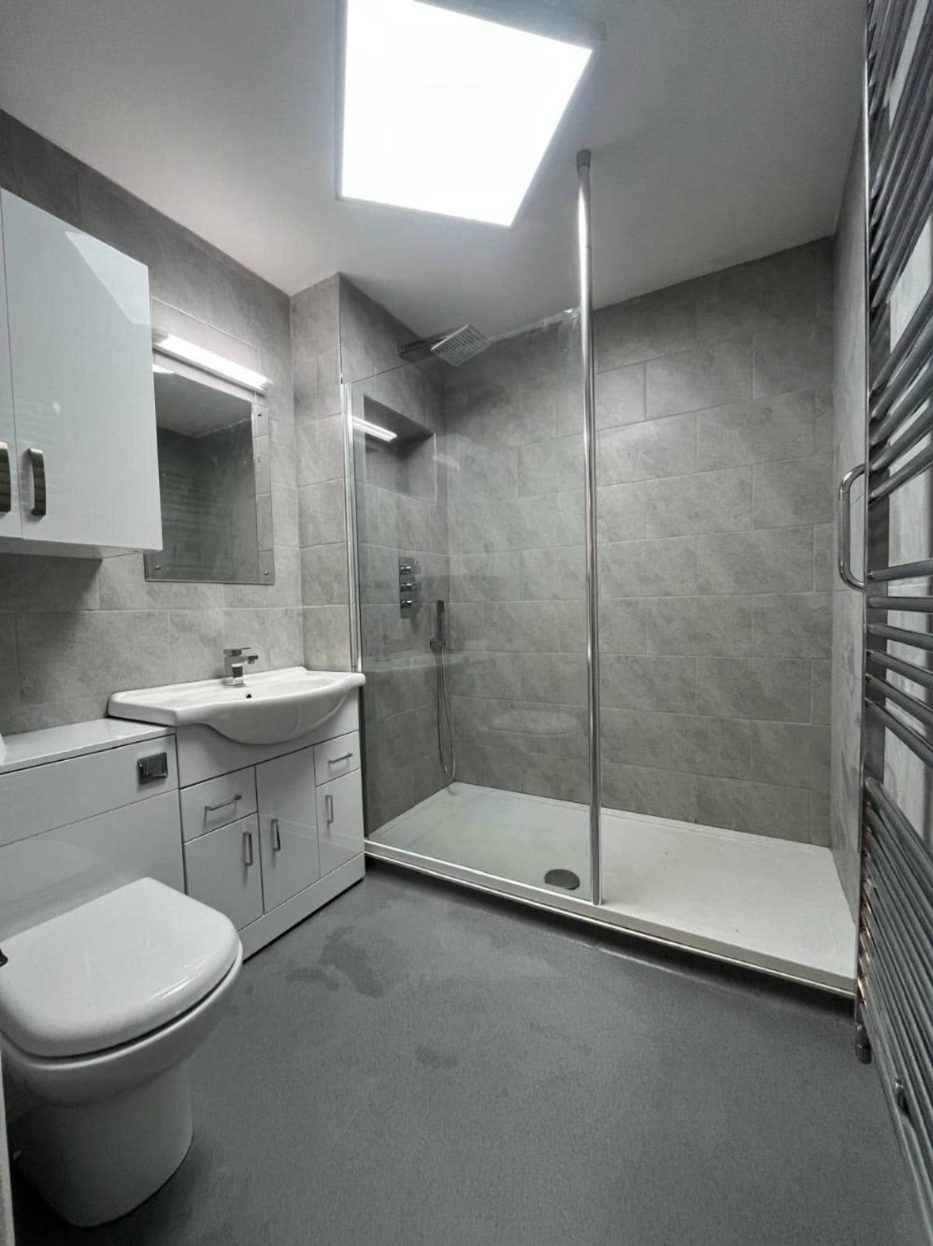Grey tiled shower room with skylight